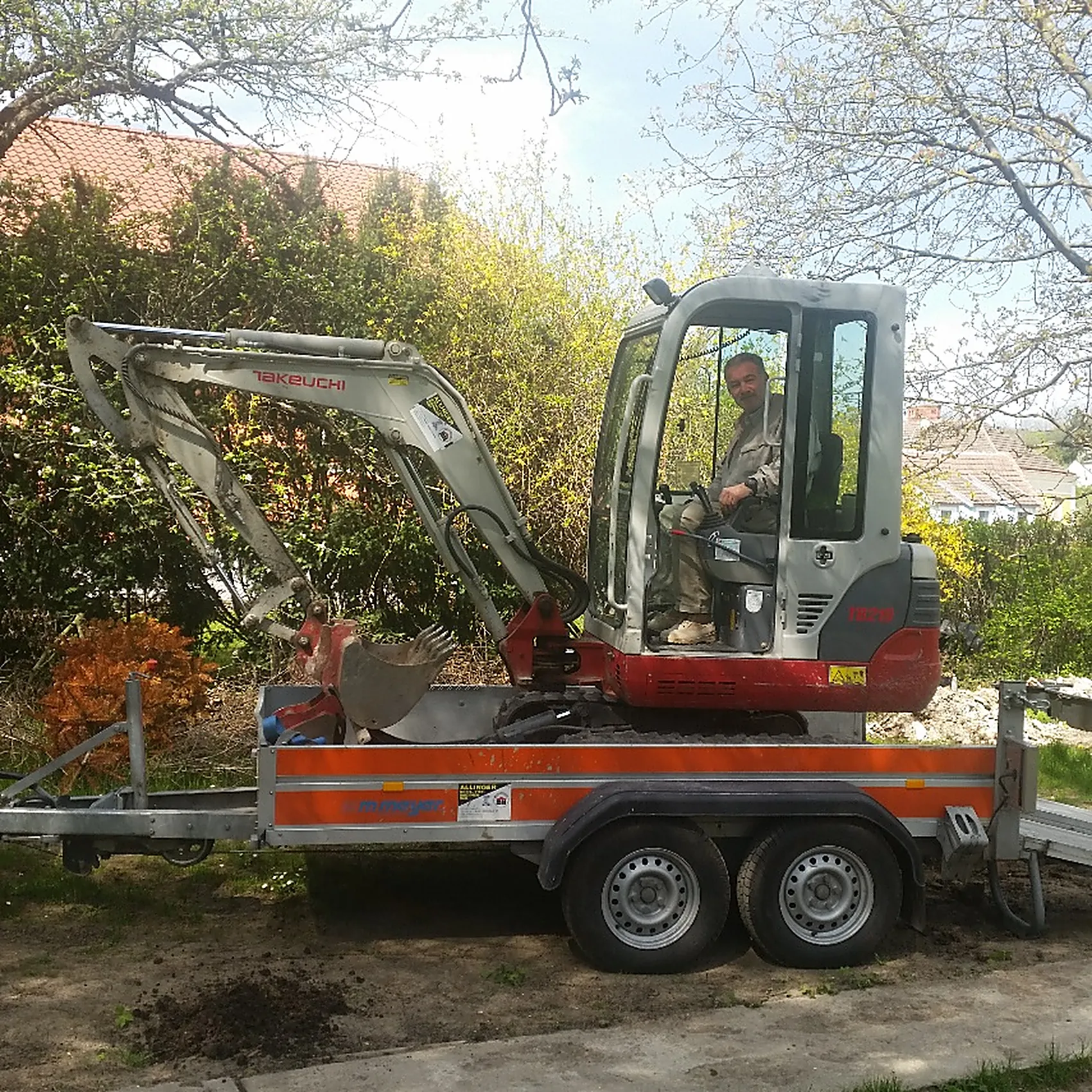 Minibagger auf dem Transport-Anhänger für die Brunnenbaustelle